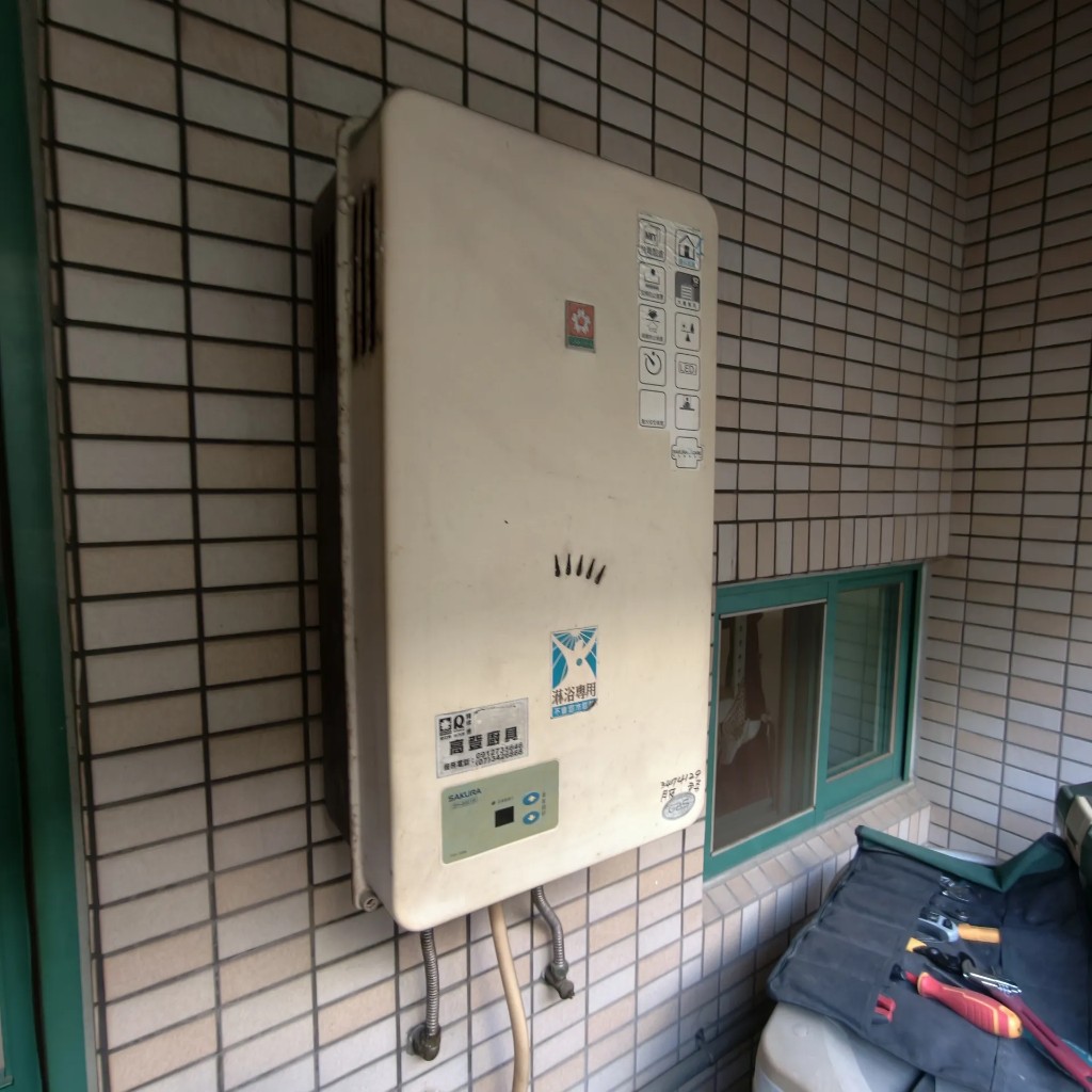 高雄鳳山區大樓陽台舊瓦斯熱水器汰換前實拍，機齡偏高外觀老化與溫控面板較舊
