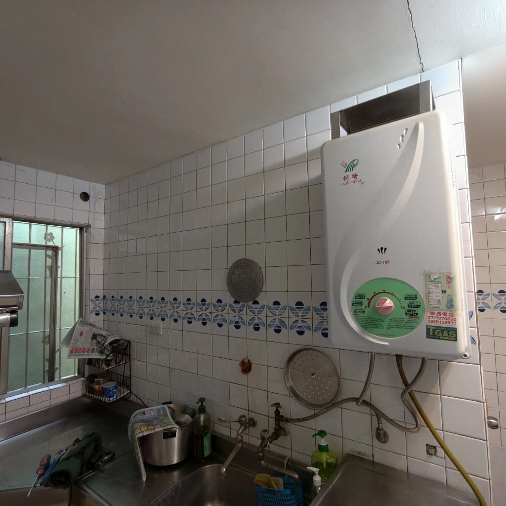 高雄前鎮區老屋內廚傳統燃氣熱水器汰舊前，白磚牆面與舊機配置