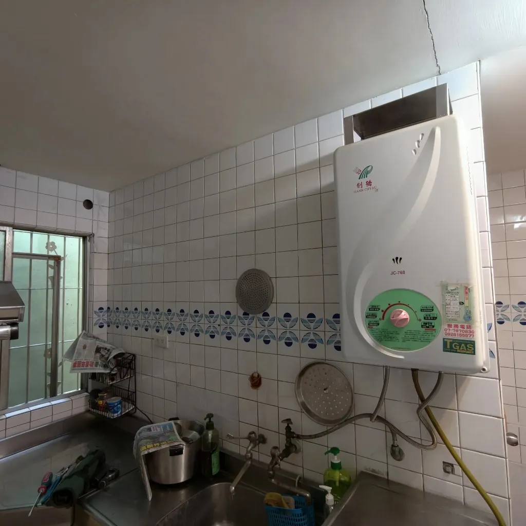 高雄前鎮區老屋內廚傳統燃氣熱水器汰舊前，白磚牆面與舊機配置